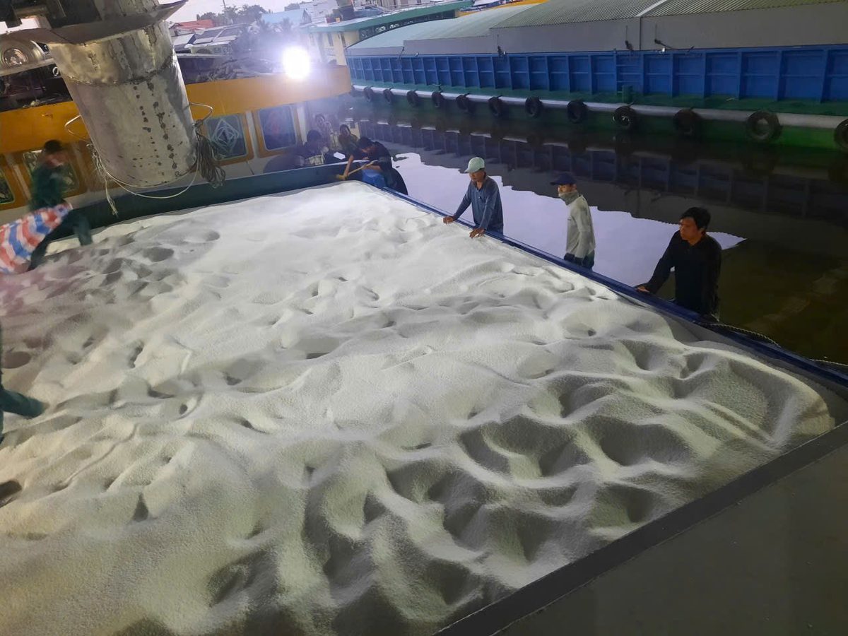 Crew loading bulk cargo onto a barge